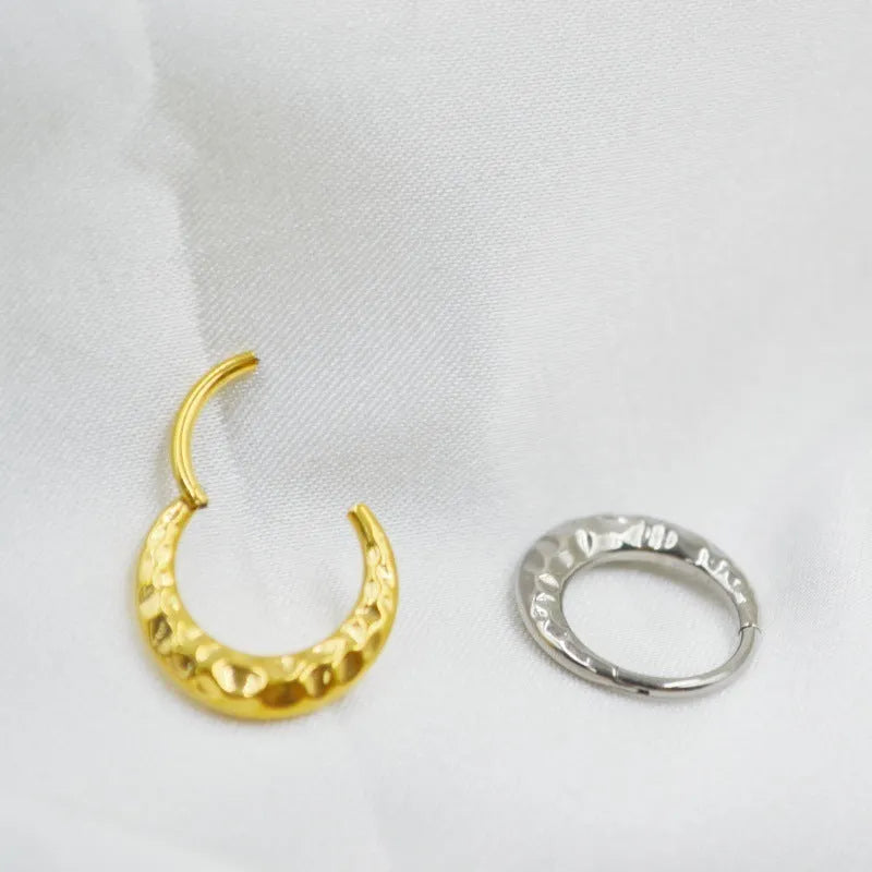 Close-up of a titanium alloy nose ring with concave-convex texture in a gold anodised finish.
