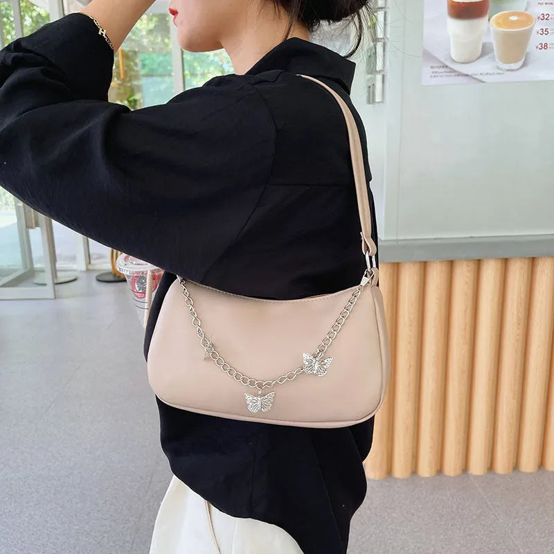 Women's black butterfly design chain underarm bag with a squared shape and three-dimensional pocket.