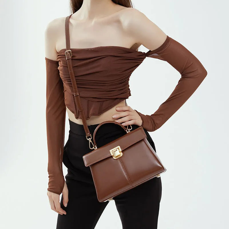 Black genuine leather shoulder bag with clasp closure showing internal compartments and adjustable strap