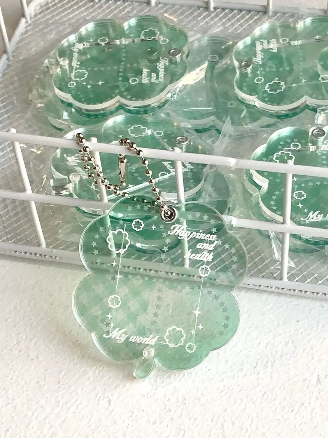 Acrylic four-leaf clover charm on a keychain for mobile phone decoration, shown in blue, green, and mint colour options.