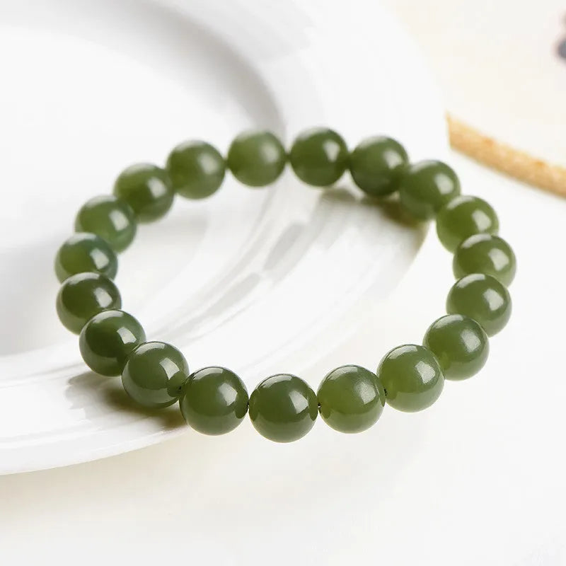 Hetian jade ball bracelet on wrist showing polished spherical beads on an elasticated string in a clear colour.