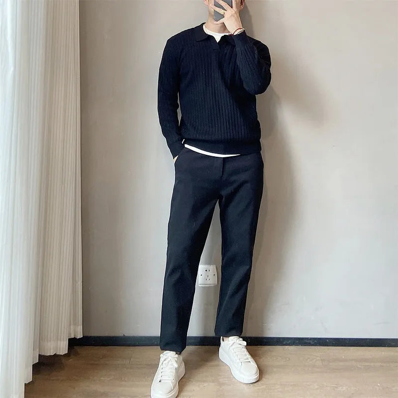Man wearing a loose grey knitted pullover sweater with long sleeves, showing textured fabric detail.