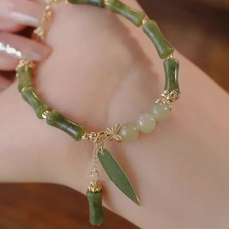 A Chinese style glass bracelet with bamboo leaf and bead designs on a wrist.