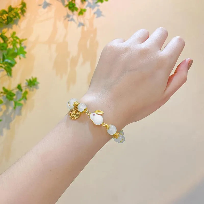 A Chinese style glass bracelet with bamboo leaf and bead designs on a wrist.