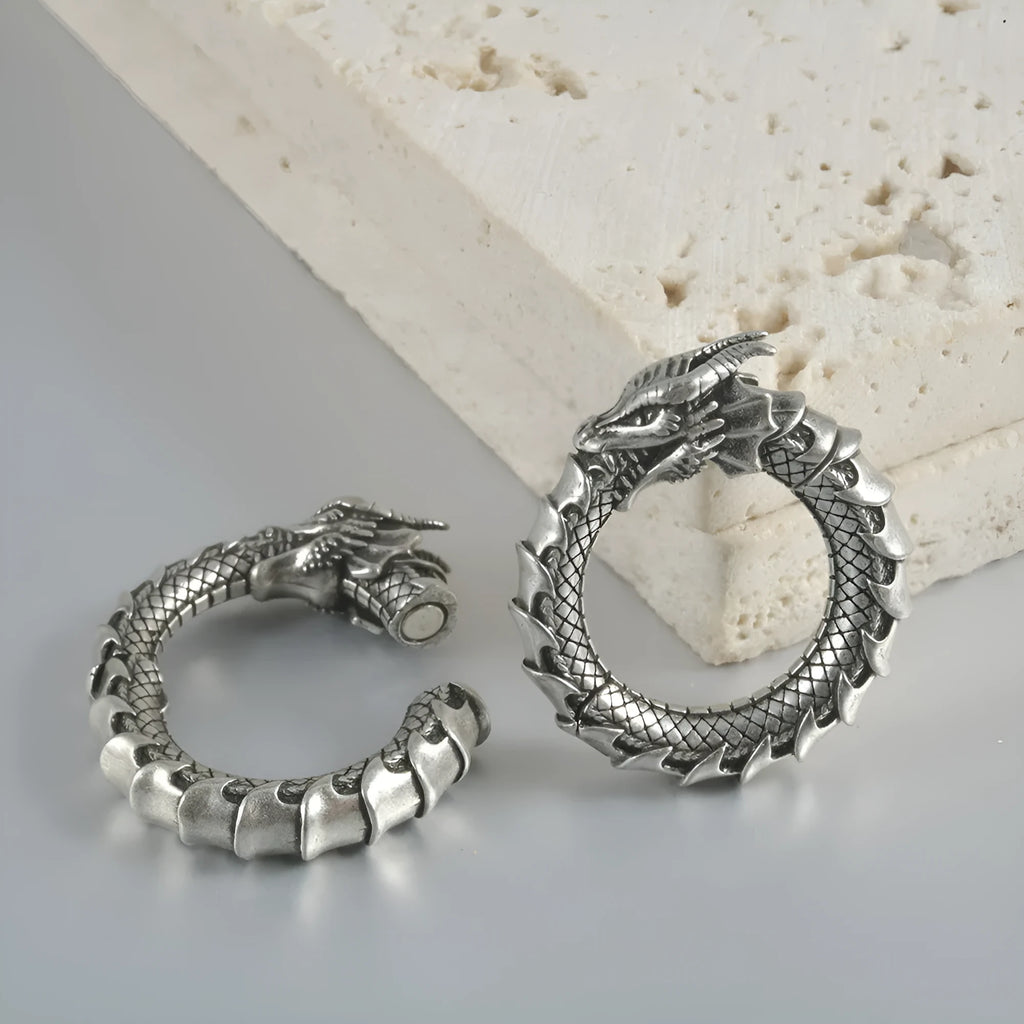 A pair of large, geometric dragon-shaped hollow out earrings in an antique silver colour.