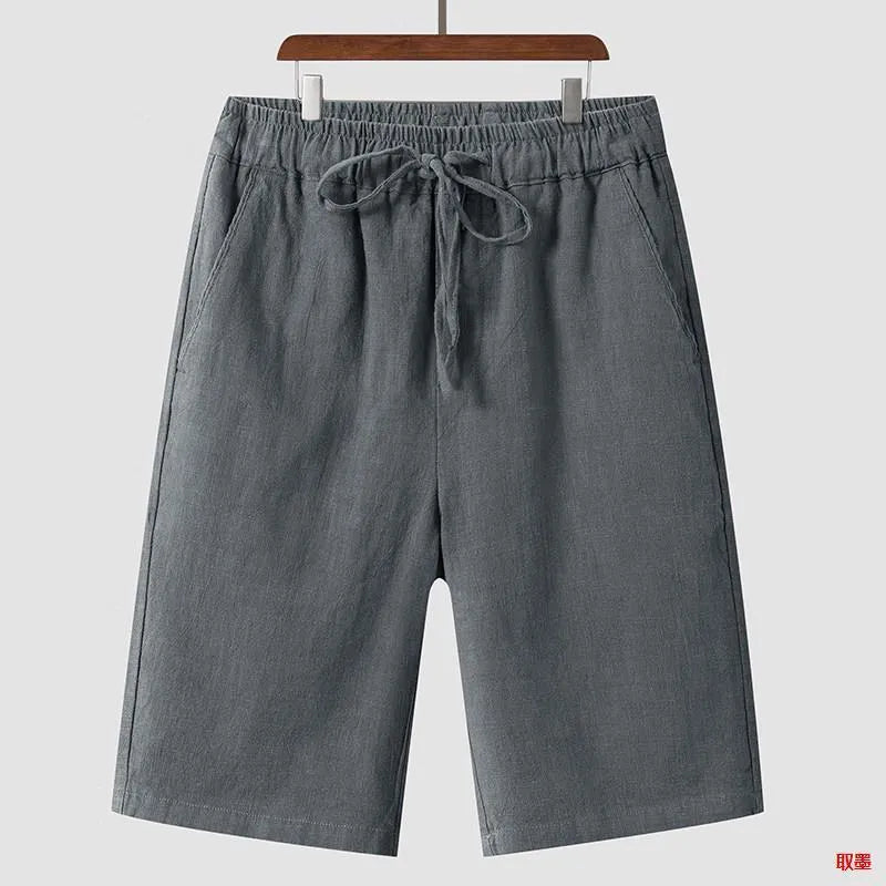 Men's beige linen shorts with loose cropped fit and elasticated waistband laid flat.