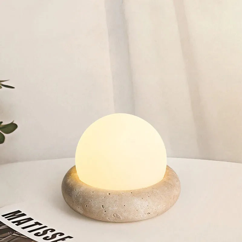 Modern cream-coloured bedside table lamp with wireless remote control on a nightstand.