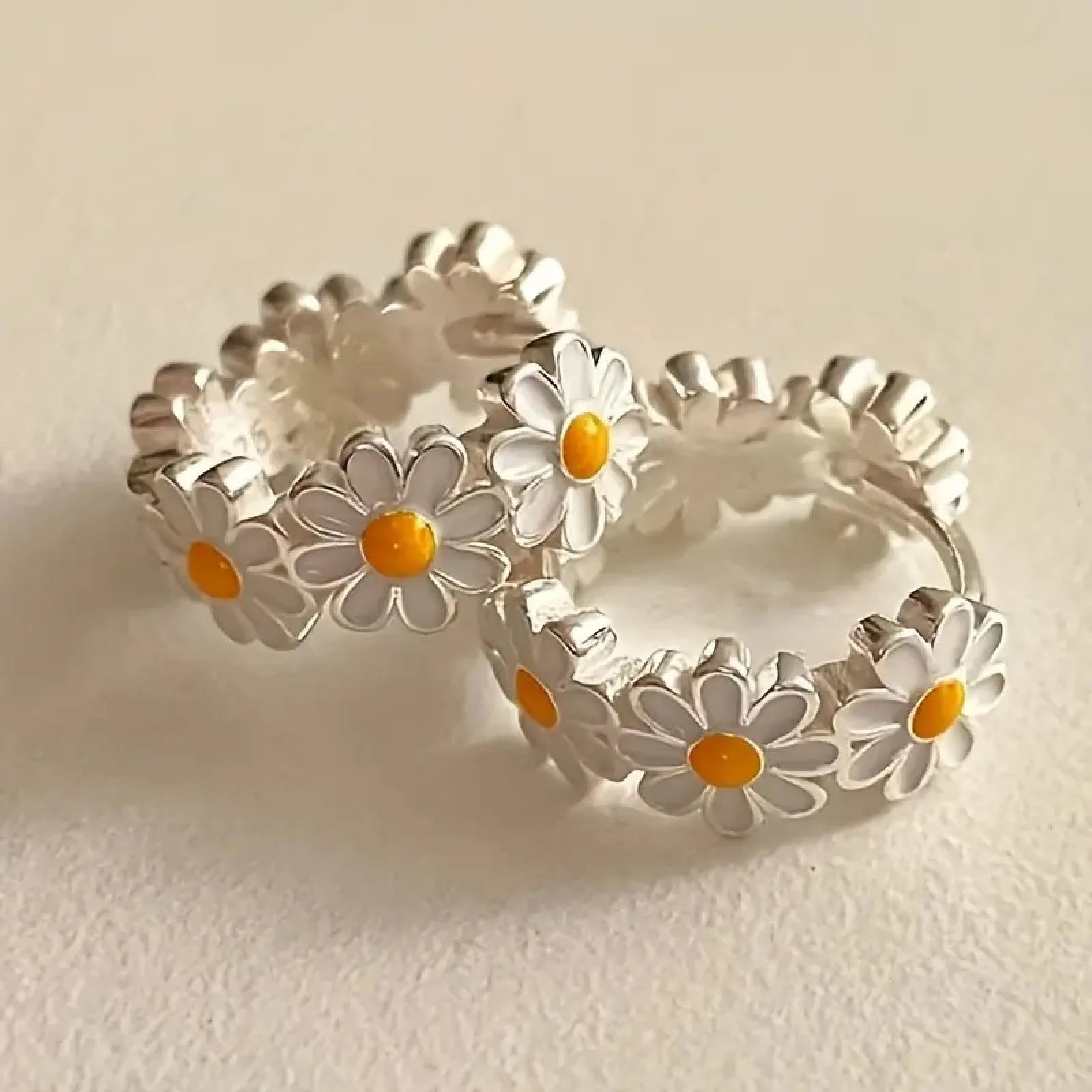 A pair of white daisy flower ring earrings with a platinum-inlaid gemstone detail.