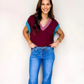 Burgundy loose-fitting V-neck sweater with contrast trim detail on cuffed short sleeves.