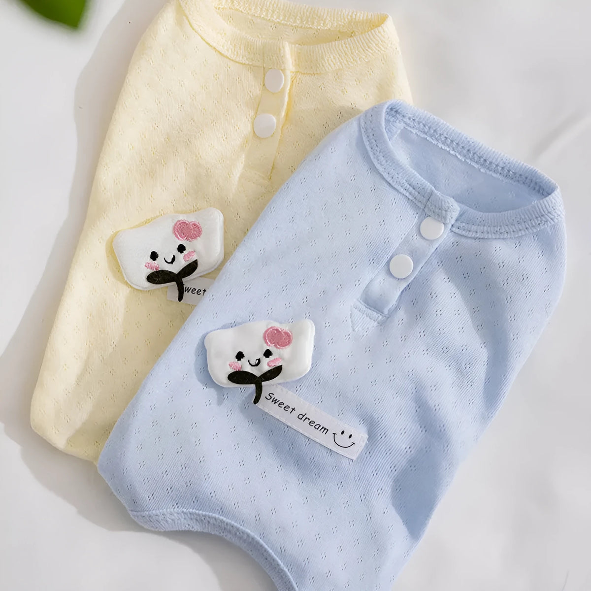 Breathable mesh pet shirt for small dogs and cats in blue or yellow with cat patch and button closure.