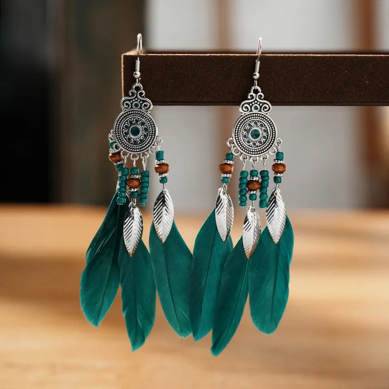 Close-up of a pair of bohemian-style feather-shaped earrings with a leaf pattern, in an alloy electroplated finish.