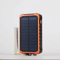 Orange and green hand-crank solar power bank with LED torch and dual USB ports showing 12000mAh capacity