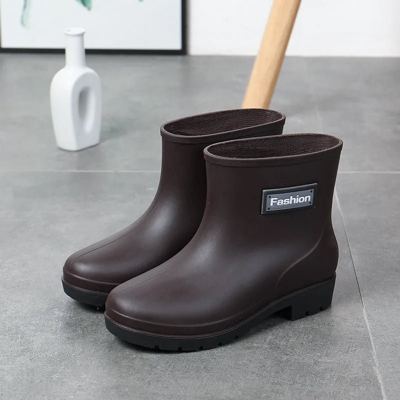 Women's black PVC mid-calf rain boot with low heel on a wet surface