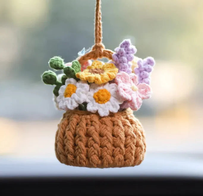 Green and white knitted car plant decoration with hanging rope on car dashboard