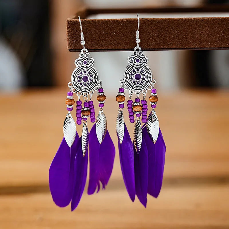 Close-up of a pair of bohemian-style feather-shaped earrings with a leaf pattern, in an alloy electroplated finish.