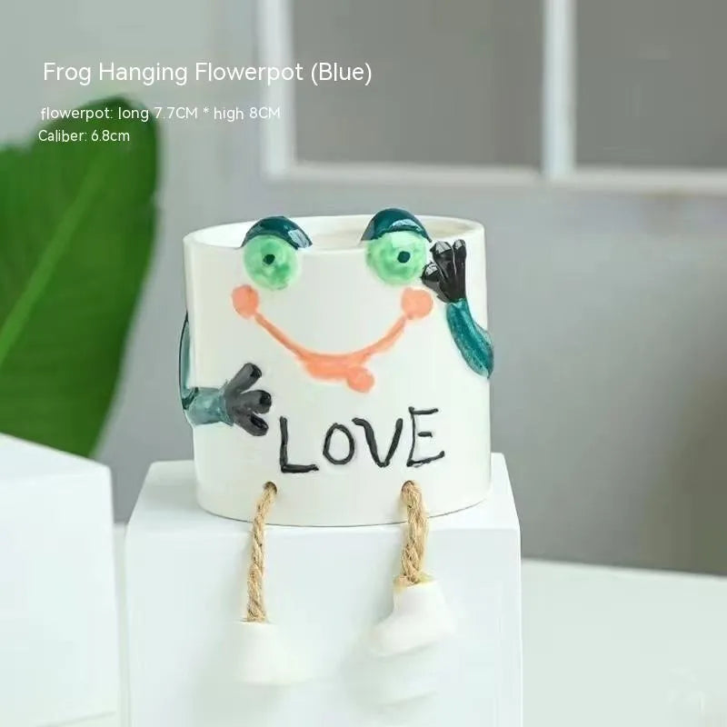 Ceramic cartoon-style succulent flowerpot with hanging foot design on desktop