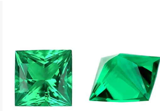 A selection of polished cultivated emerald gemstones in round, heart, and princess cuts on a white background.