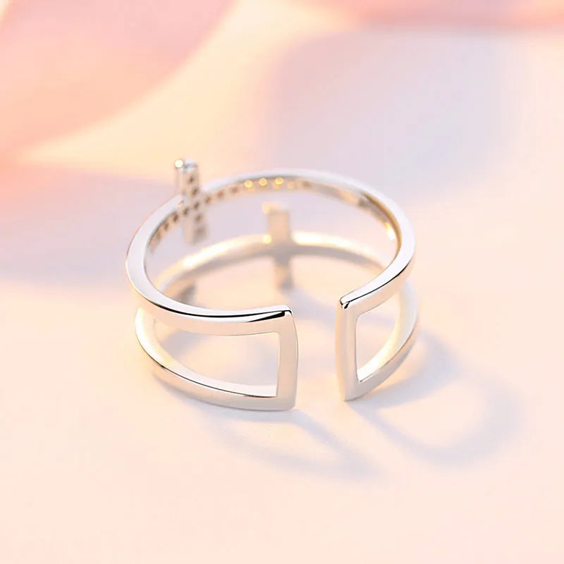 Adjustable open ring showing double cross design with zircon stones and sterling silver inlay on copper.