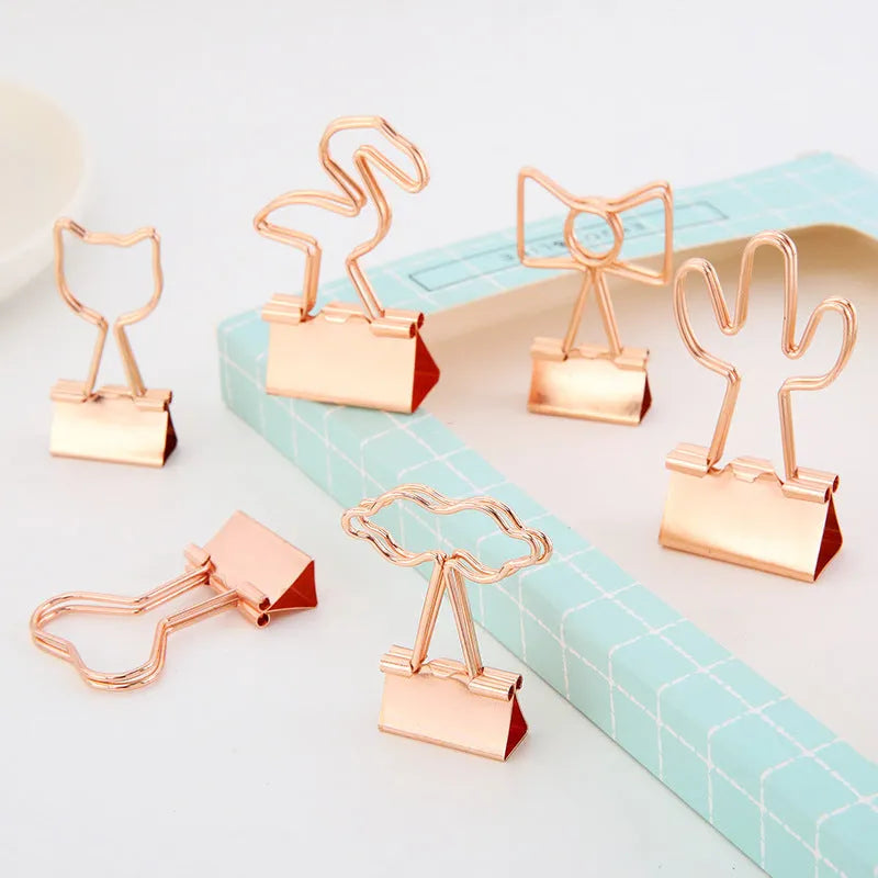 Gold-coloured decorative office paper clips with long tail designs including flamingo, love, cloud, cat, cactus, and bow shapes