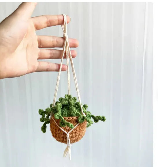Green and white knitted car plant decoration with hanging rope on car dashboard