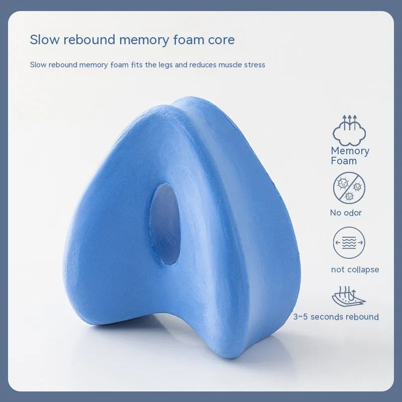 Heart-shaped dark blue memory foam leg pillow for adults on a bed.