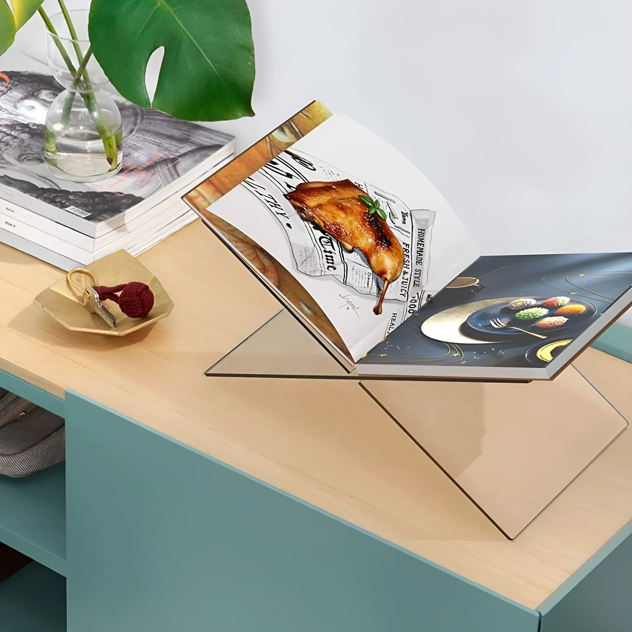 Clear acrylic X-shaped book display rack holding a book on a desktop