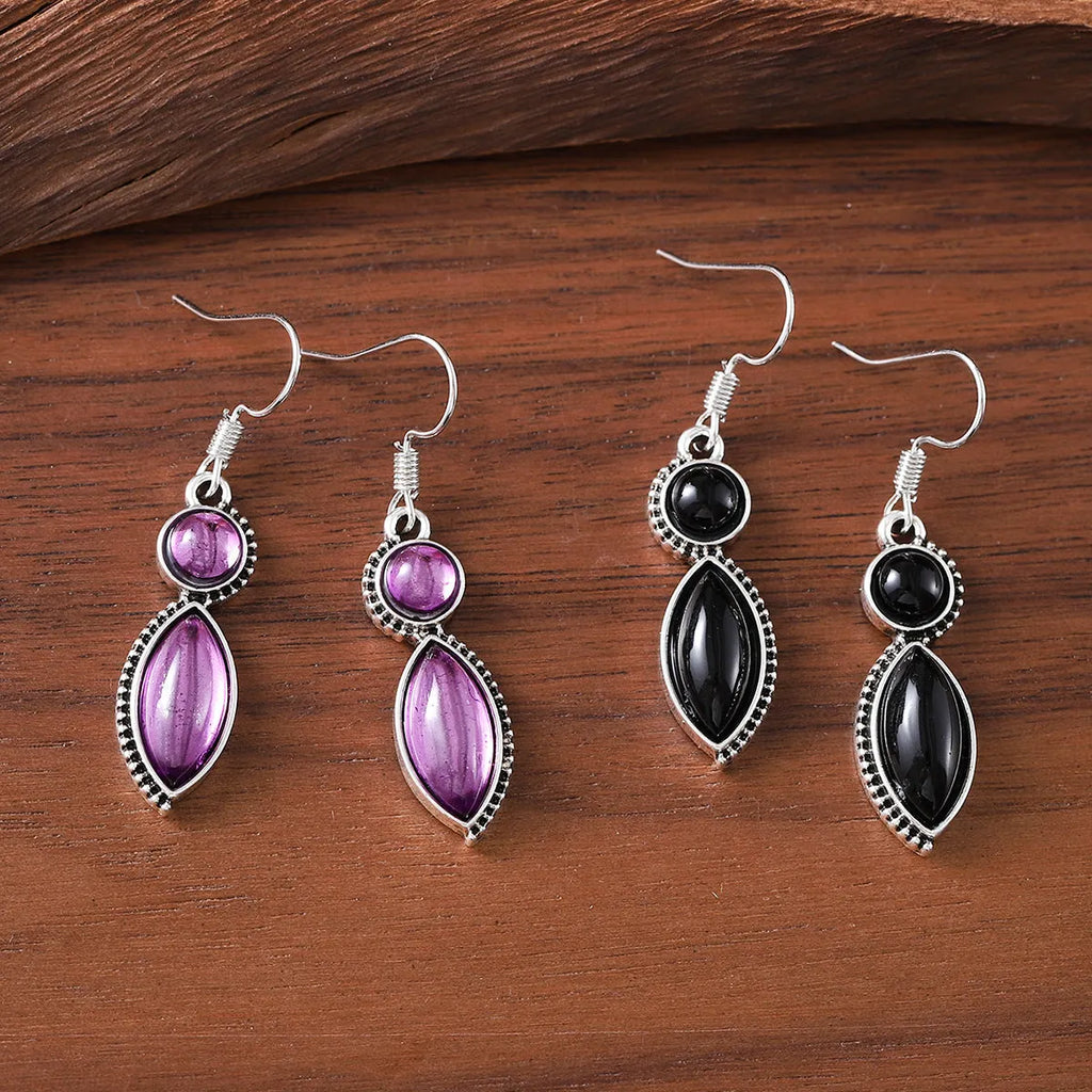 A pair of vintage geometric drop earrings with black and purple stones in a bohemian style.