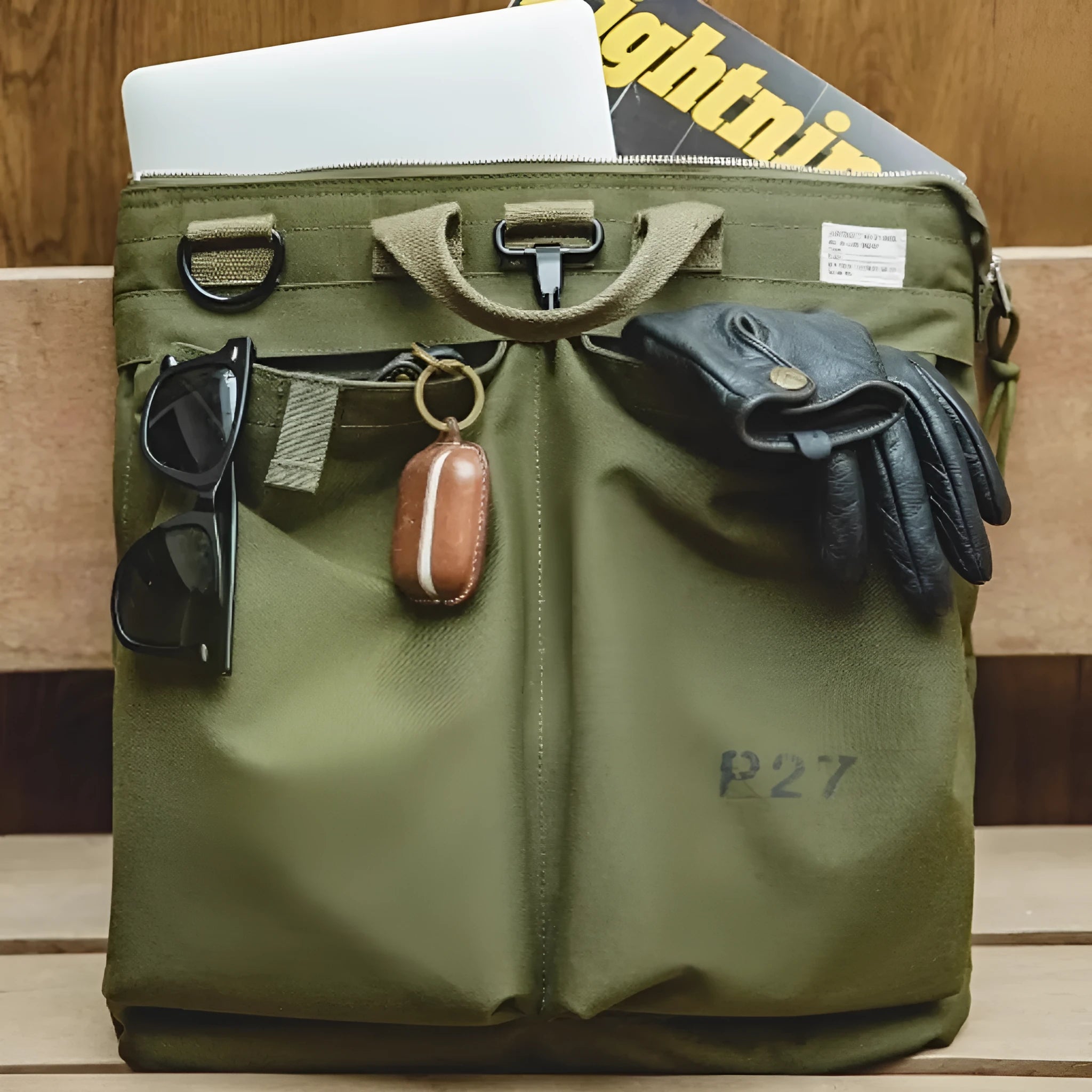Canvas crossbody messenger bag in military green with shoulder strap and hard handle showing laptop compartment