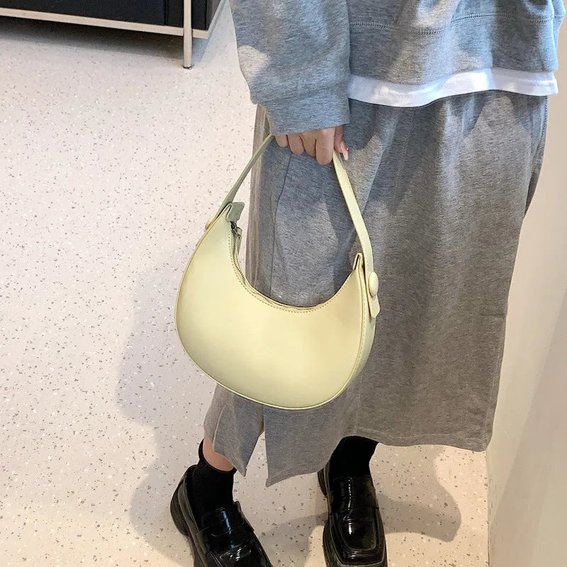 Women's retro-style dumpling-shaped PU leather shoulder bag in cream yellow, showing sandwich pocket.