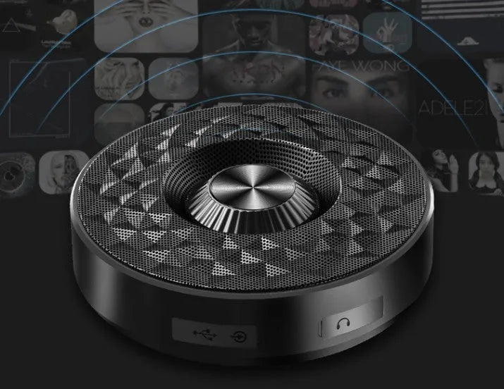 Compact black/orange/silver white portable Bluetooth speaker on a surface, showing its 360-degree grille.