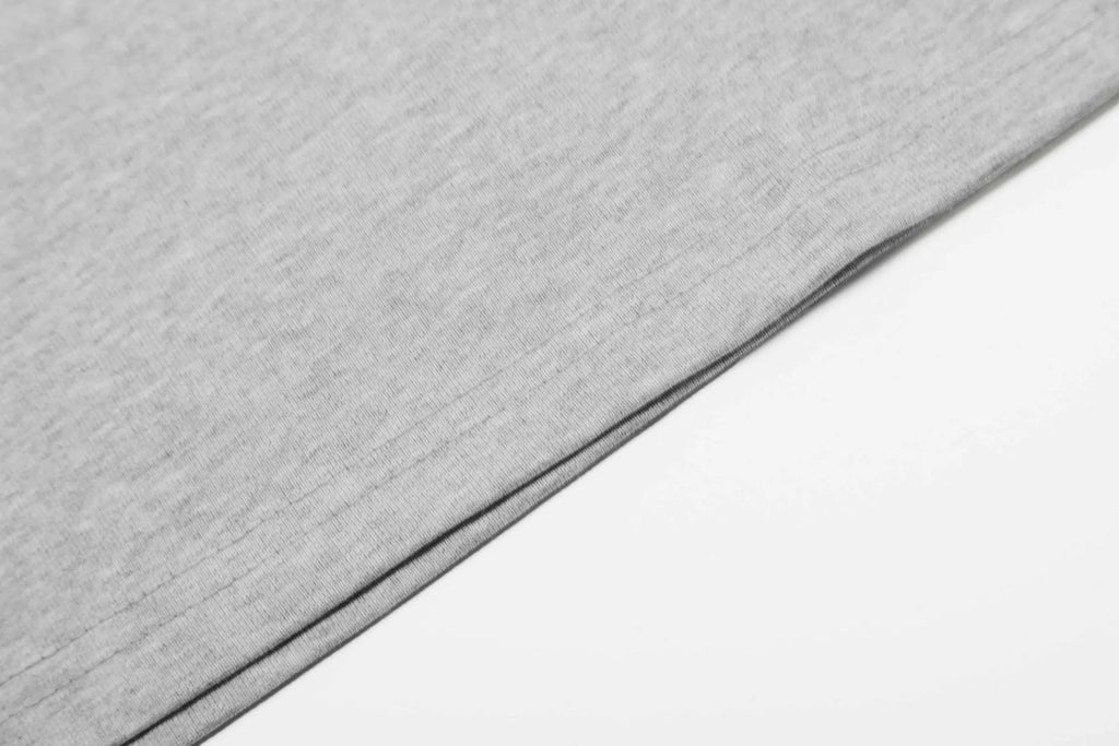 Man wearing a grey loose fit cotton long sleeve pullover with a simple retro design.