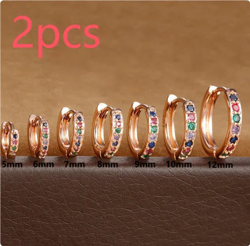 A pair of small circular zircon stud earrings with a metallic finish, shown next to a ruler indicating available sizes from 5mm to 12mm.