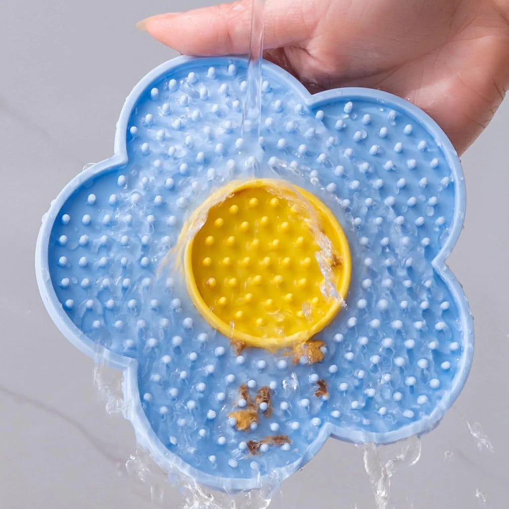 Flower-shaped blue silicone pet lick mat with suction cups on a smooth surface