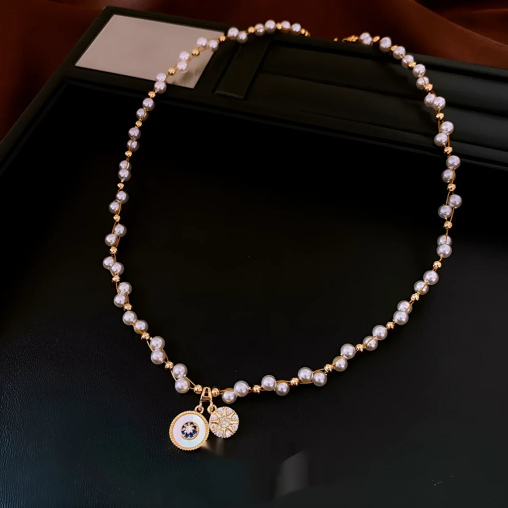 Gold electroplated zircon and imitation pearl round pendant on an adjustable clavicle chain necklace.