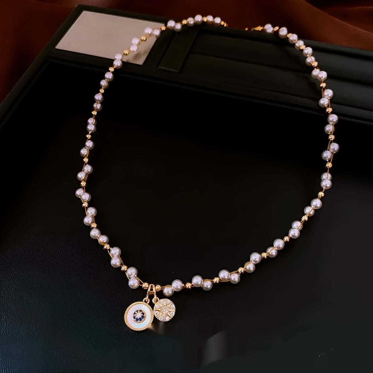 Gold electroplated zircon and imitation pearl round pendant on an adjustable clavicle chain necklace.