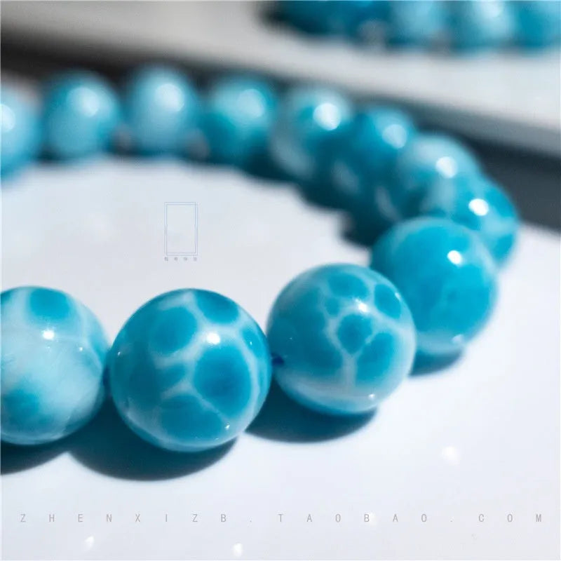 Blue natural crystal sea-pattern stone and bodhi seed bracelet with pearl accents on a wrist.