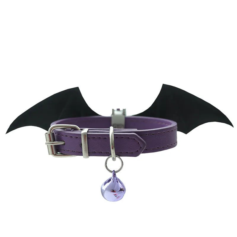 Small black leather dog collar with red devil wings and a golden bell attached.