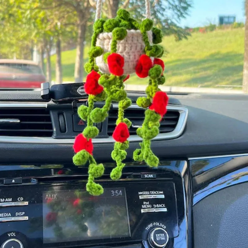 Green and white knitted car plant decoration with hanging rope on car dashboard