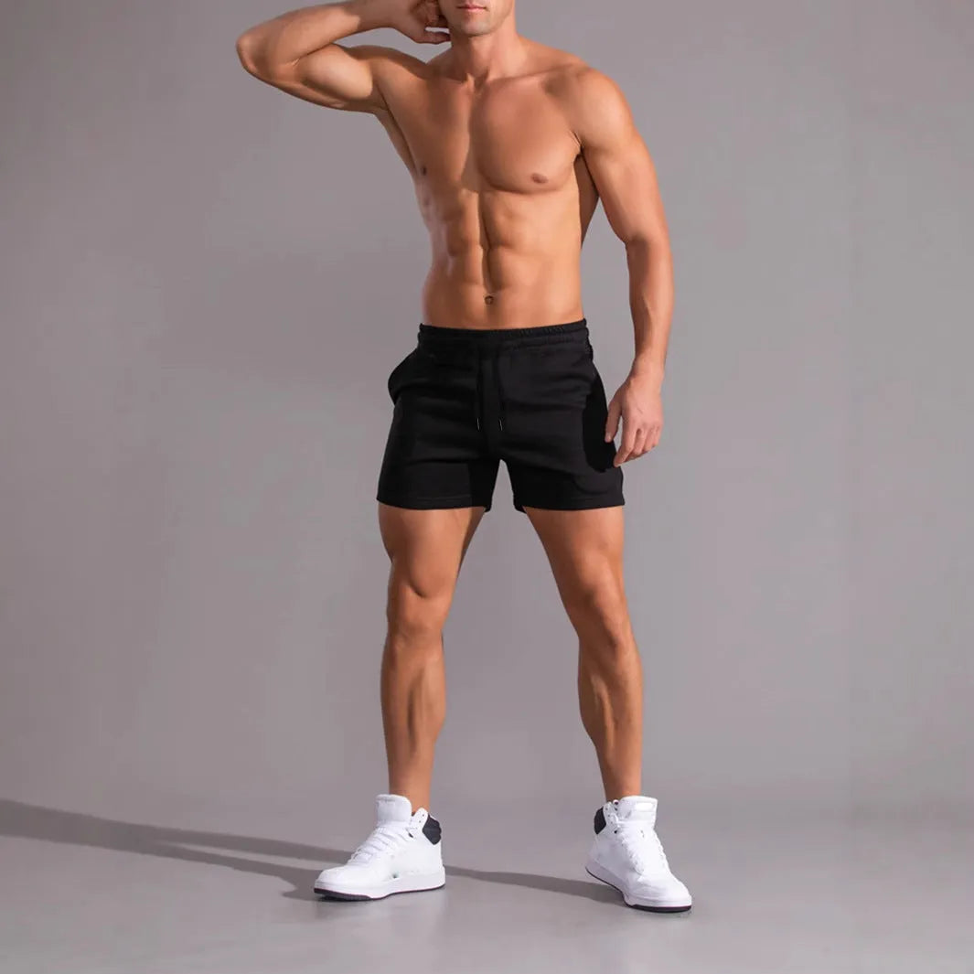 Men's black, khaki, and light brown elastic drawstring shorts laid flat, showing loose fit and adjustable waistband.