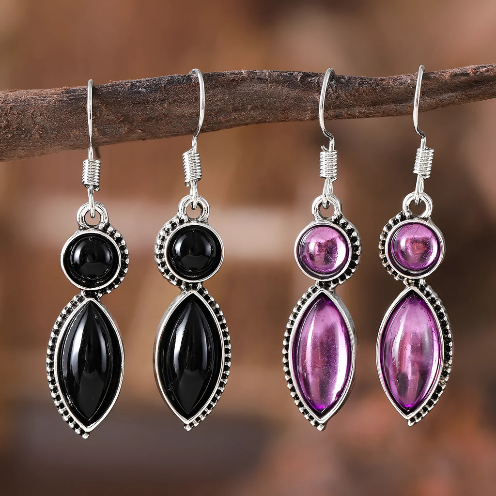 A pair of vintage geometric drop earrings with black and purple stones in a bohemian style.