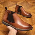 Men's black formal leather boots with pointed toe design and square heel on wooden floor