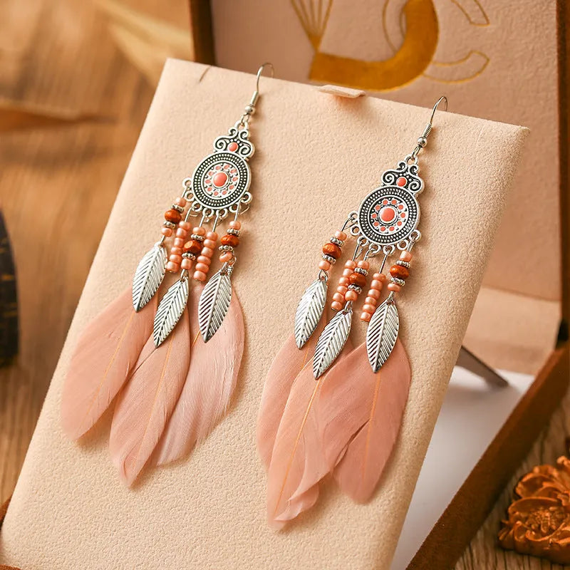 Close-up of a pair of bohemian-style feather-shaped earrings with a leaf pattern, in an alloy electroplated finish.