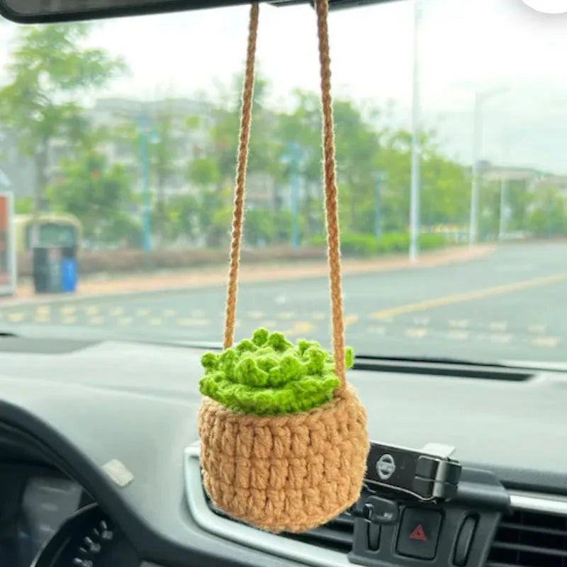 Green and white knitted car plant decoration with hanging rope on car dashboard