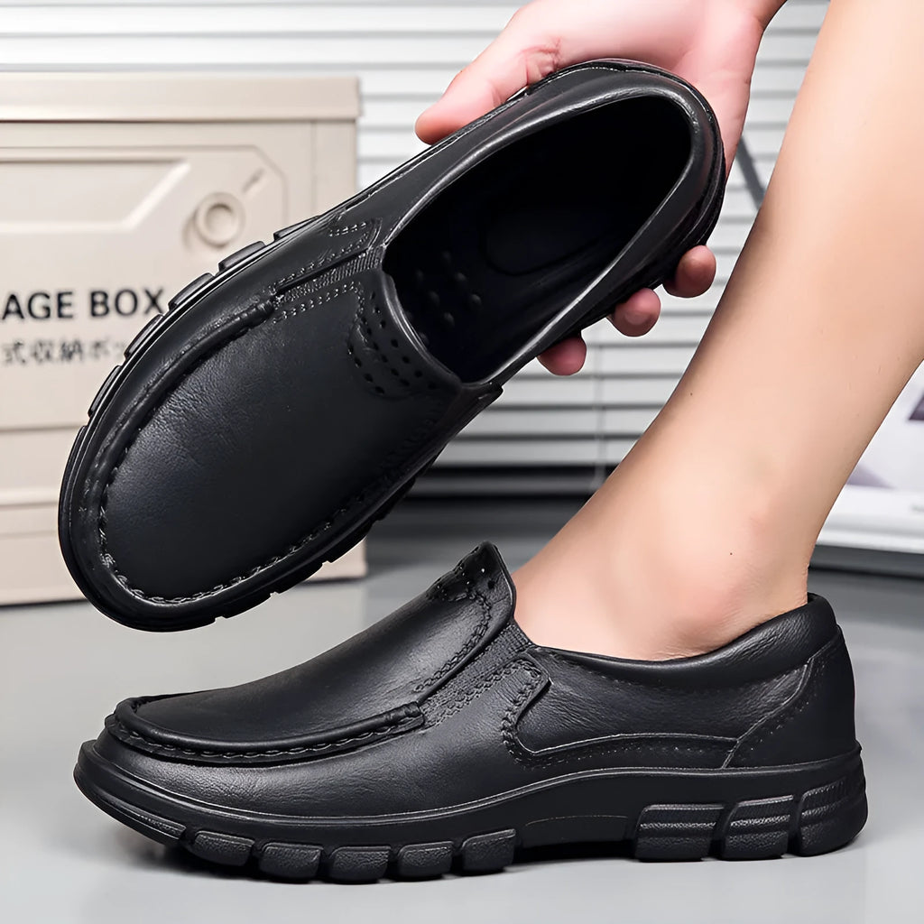 Men's black slip-on work shoes with a mid-top waterproof platform sole on a white background.