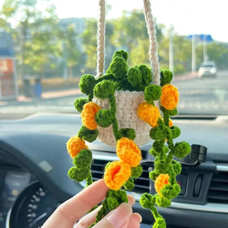 Green and white knitted car plant decoration with hanging rope on car dashboard