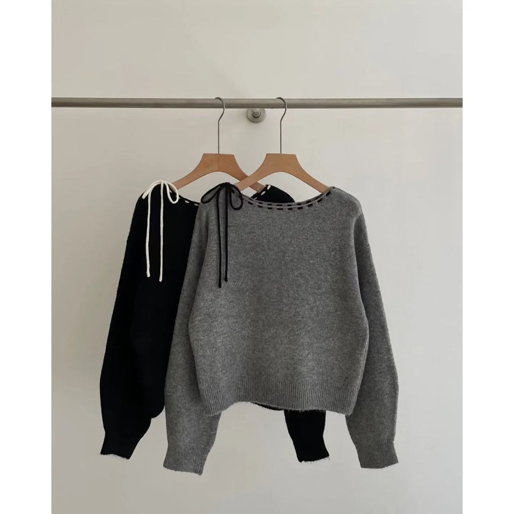 A grey loose-fitting women's knitwear pullover sweater on a hanger.