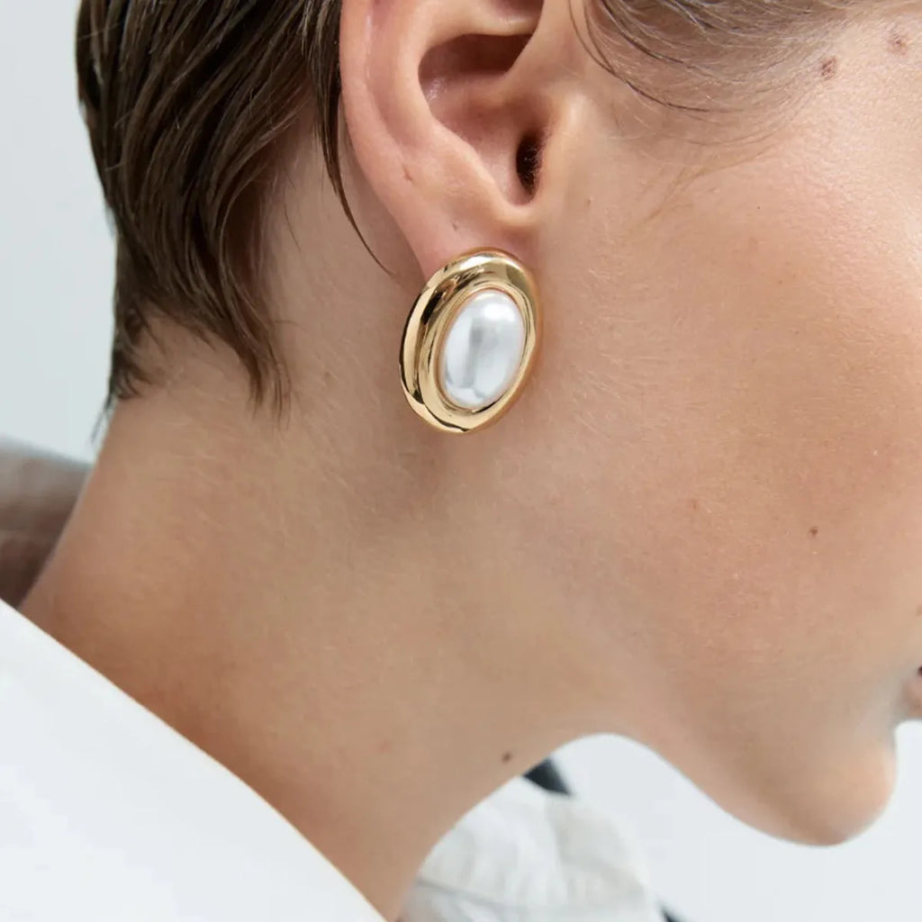 A pair of women's stainless steel stud earrings with a vintage-style pearl and electroplated finish.