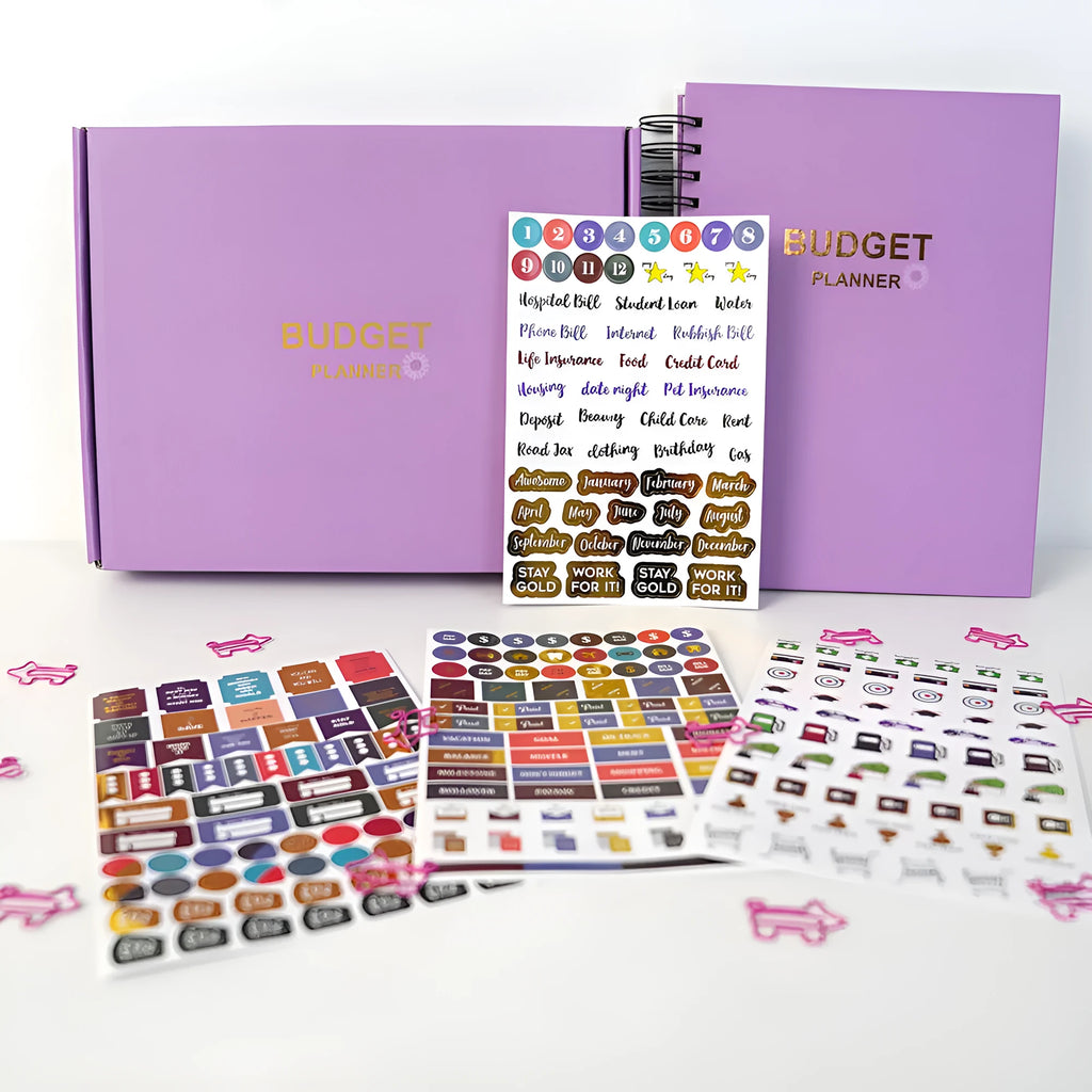 Purple coil-bound A5 financial planning notebook with pen, stickers, and paper clips for monthly budgeting