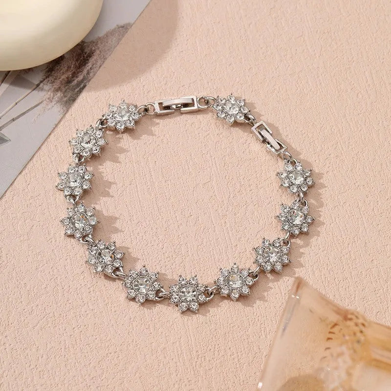 Gold tone flower-shaped bracelet with blue crystal gems on a wrist.