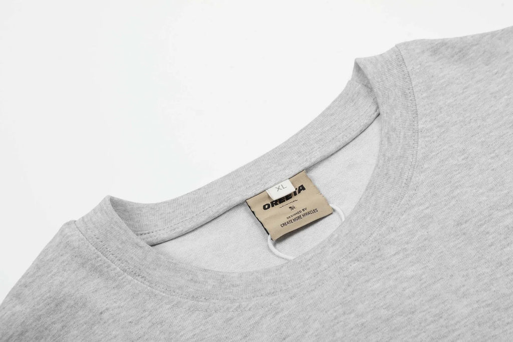 Man wearing a grey loose fit cotton long sleeve pullover with a simple retro design.